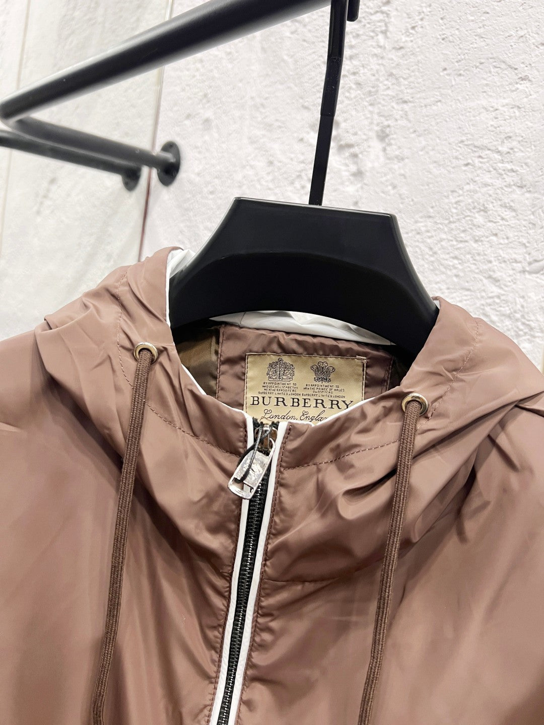 Taupe hooded jacket on hanger with visible inner lining and full front zip