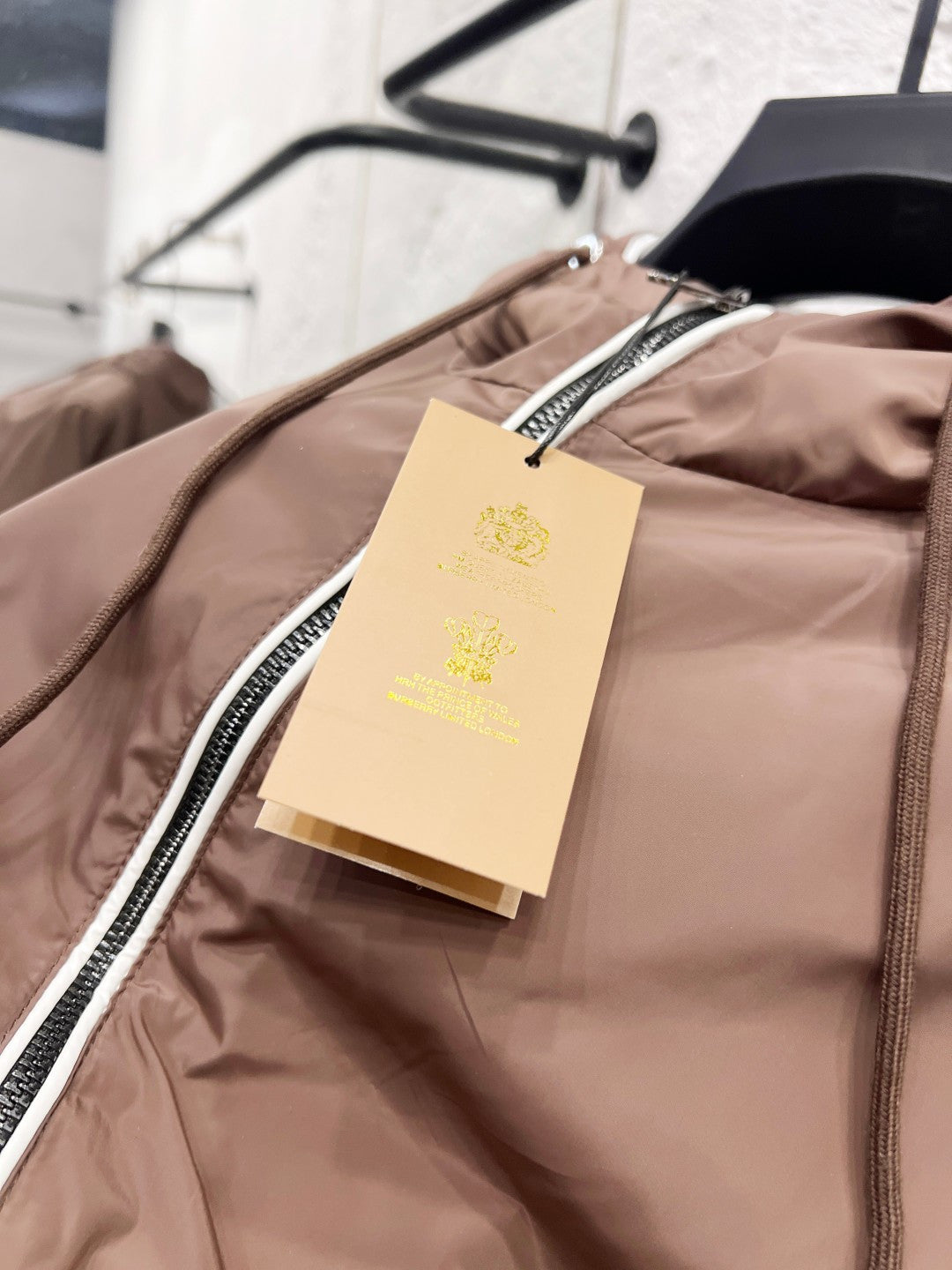 Taupe jacket interior view with hanging tag and central zip