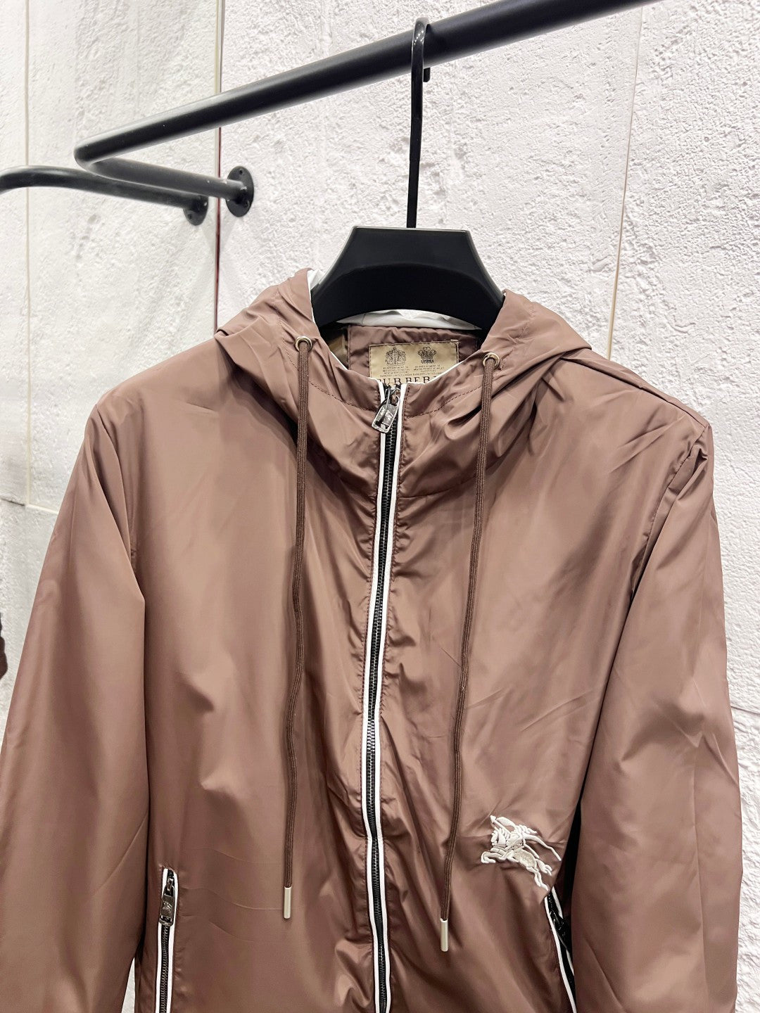 Taupe hooded jacket with front zipper, chest pocket zips, and small horse logo