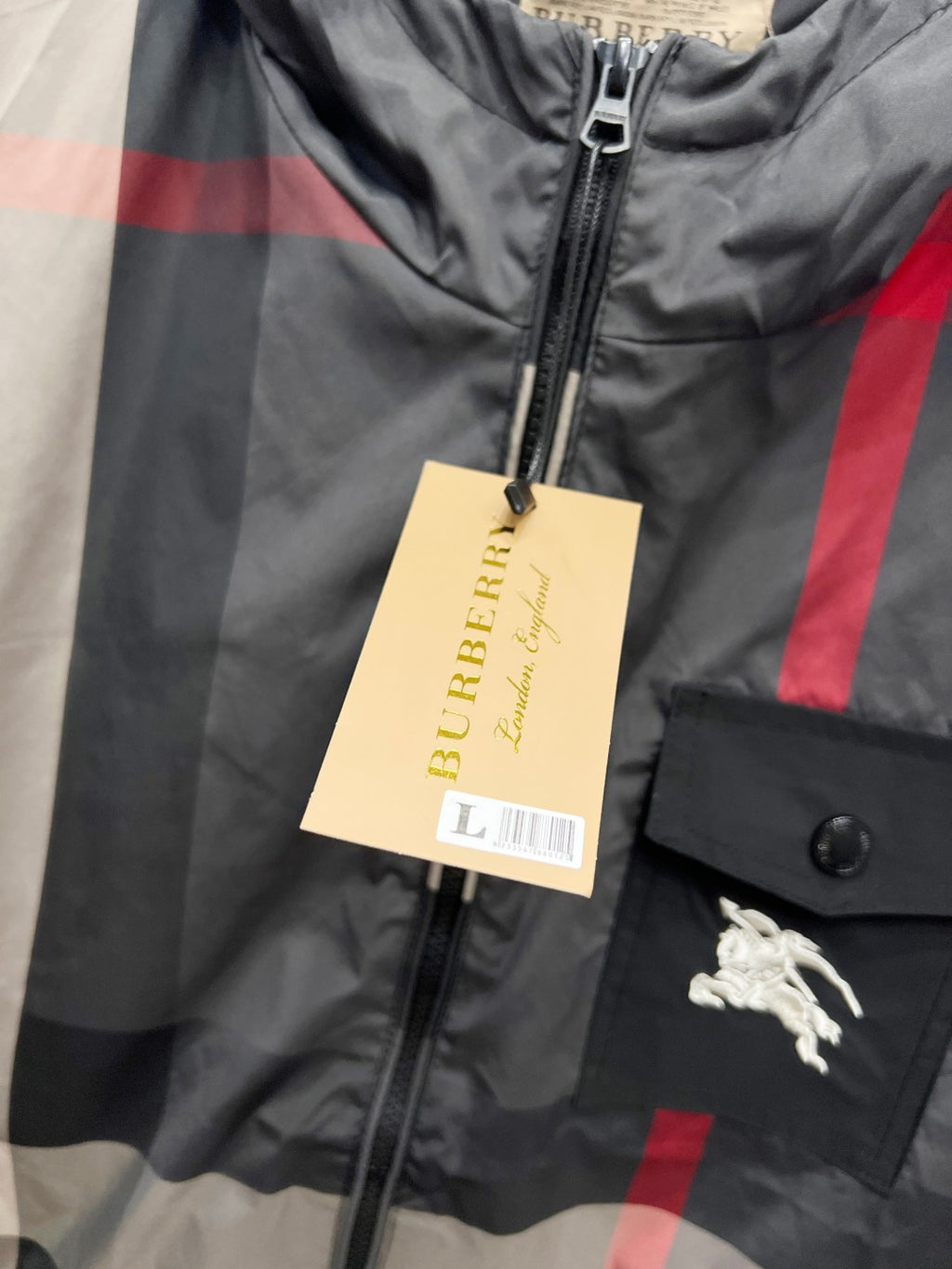 Burberry jacket front with hanging fabric tag on zipper placket, dark gray check