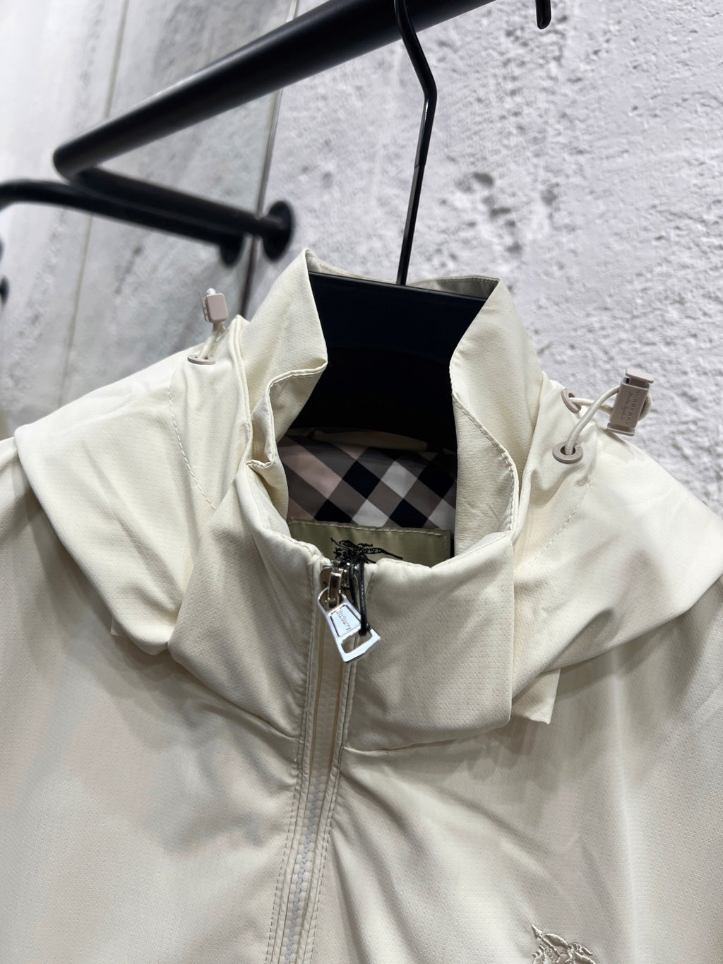 White hooded jacket with inner hood lining and front zipper opening with metal pull