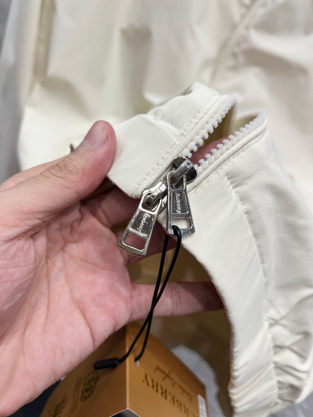 White jacket fabric cuff with zipper and metal pull hardware close-up