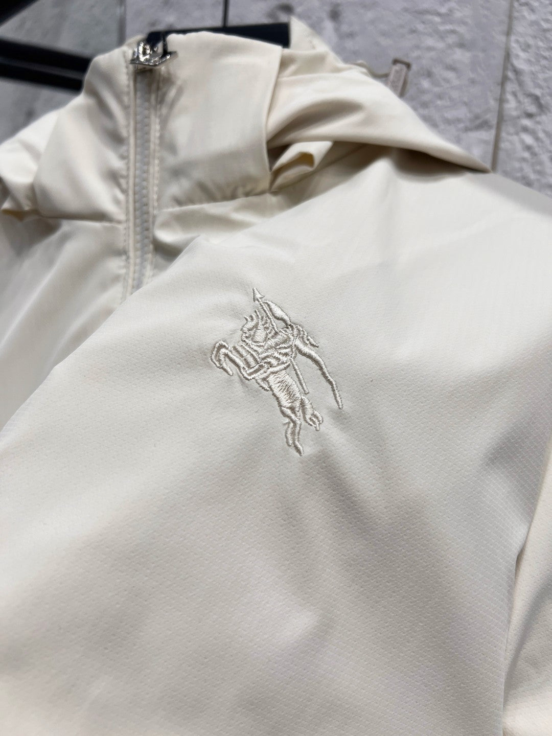 White jacket chest with embroidered rider logo and front zipper placket