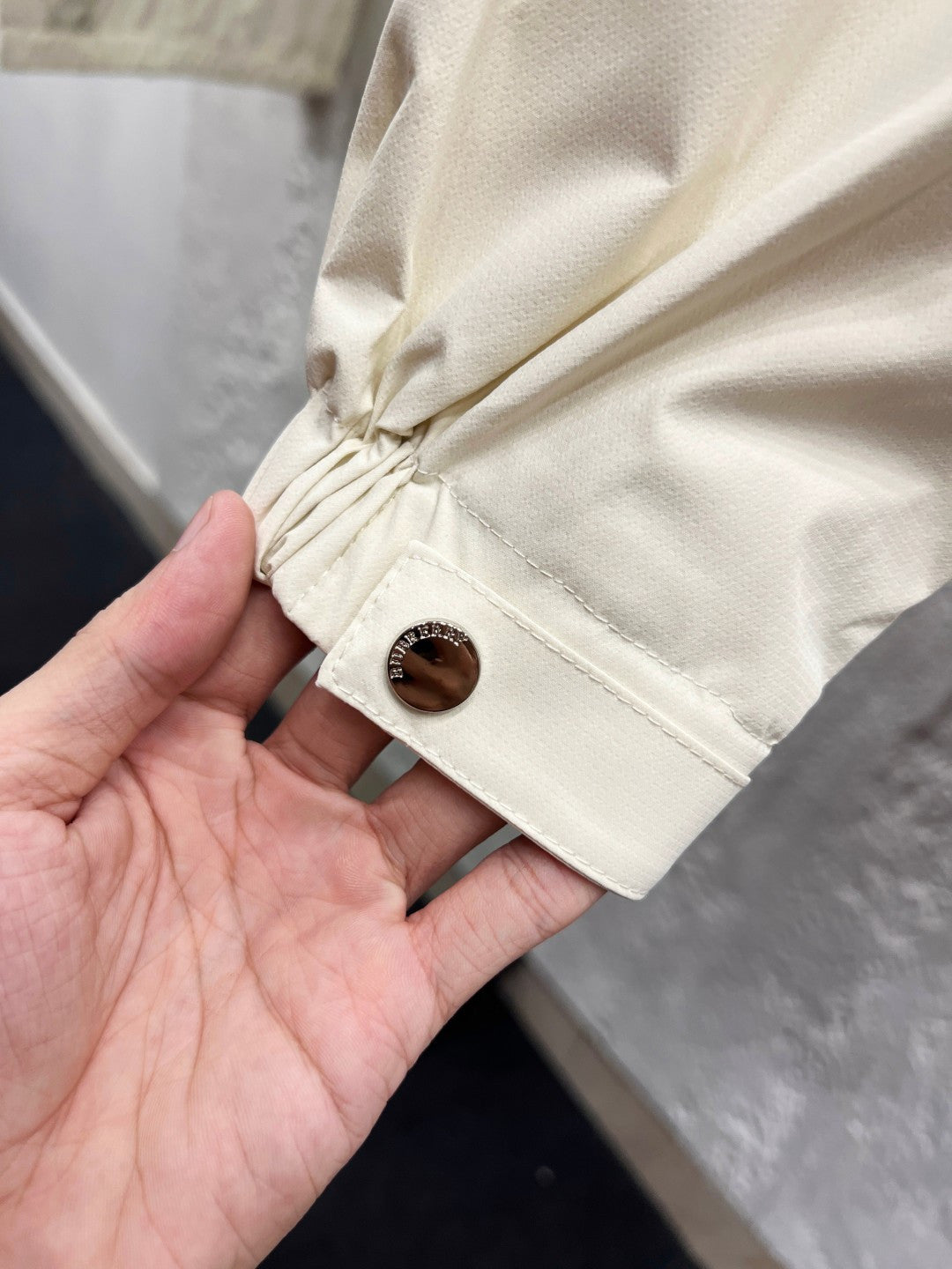 White jacket sleeve cuff with elastic drawstring and snap button detail close-up
