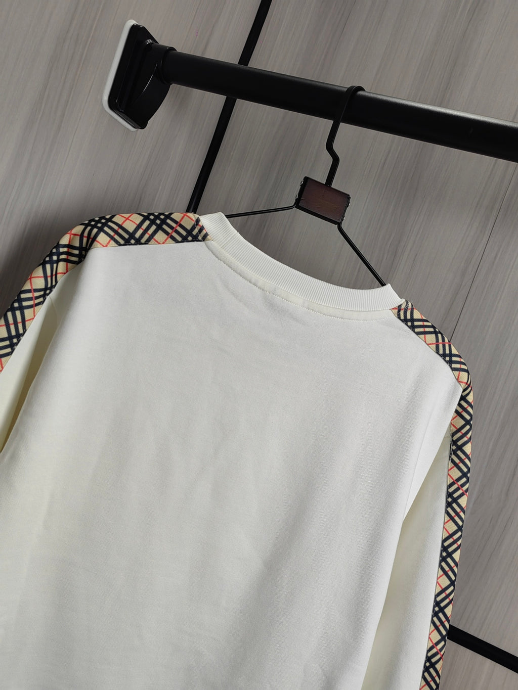 Burberry kids crewneck sweatshirt side view in cream with check trim at shoulder.