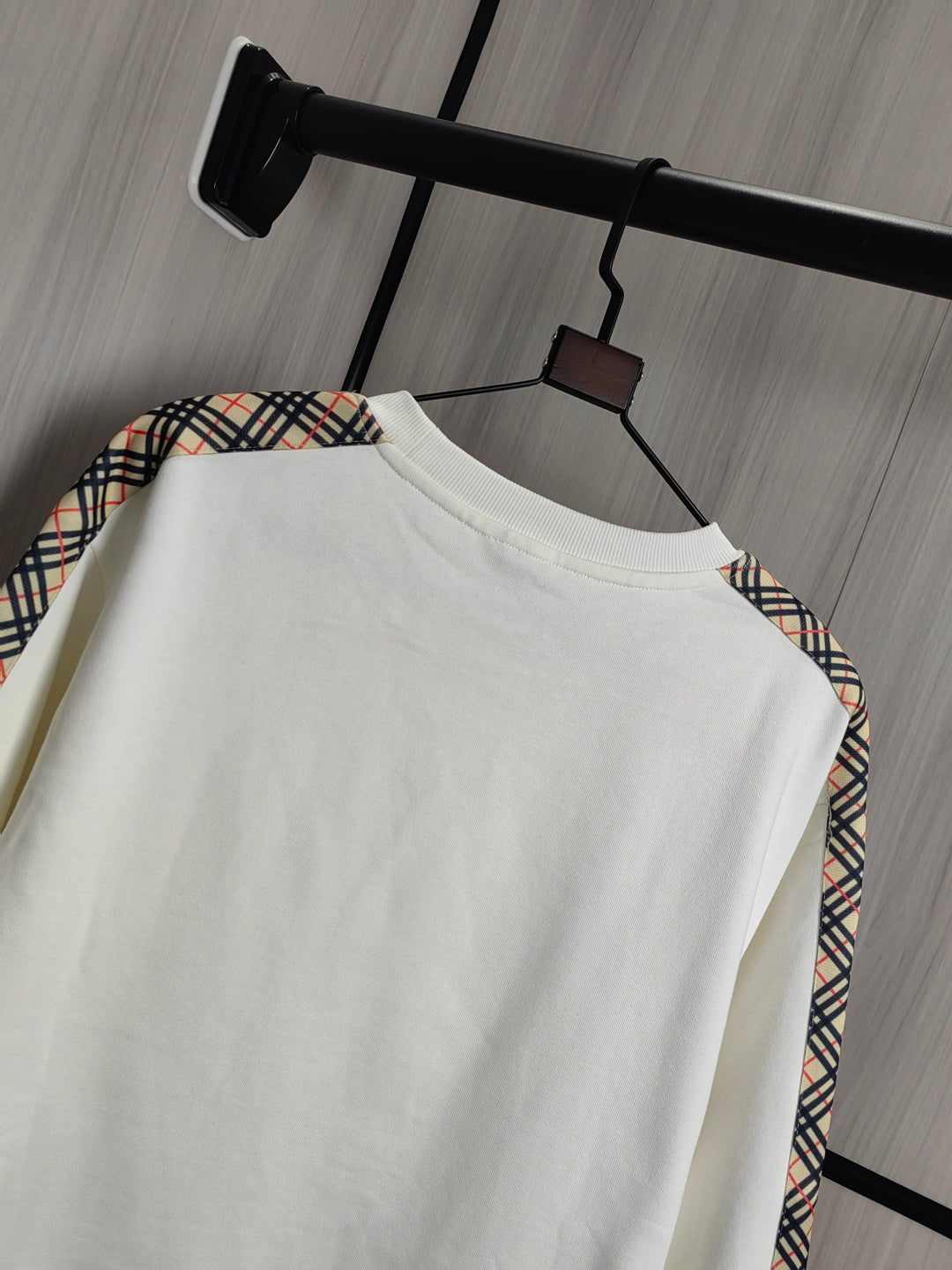 Burberry kids crewneck sweatshirt side view in cream with check trim at shoulder.