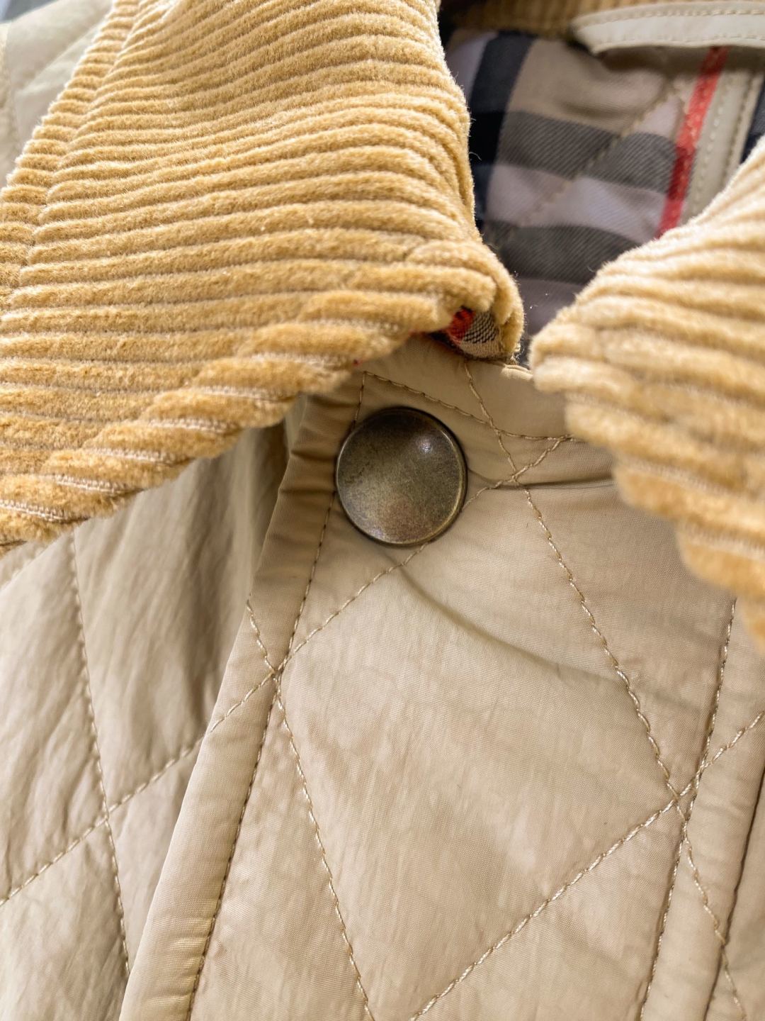 Beige ribbed cuff close-up with quilted front stitching and metal snap button
