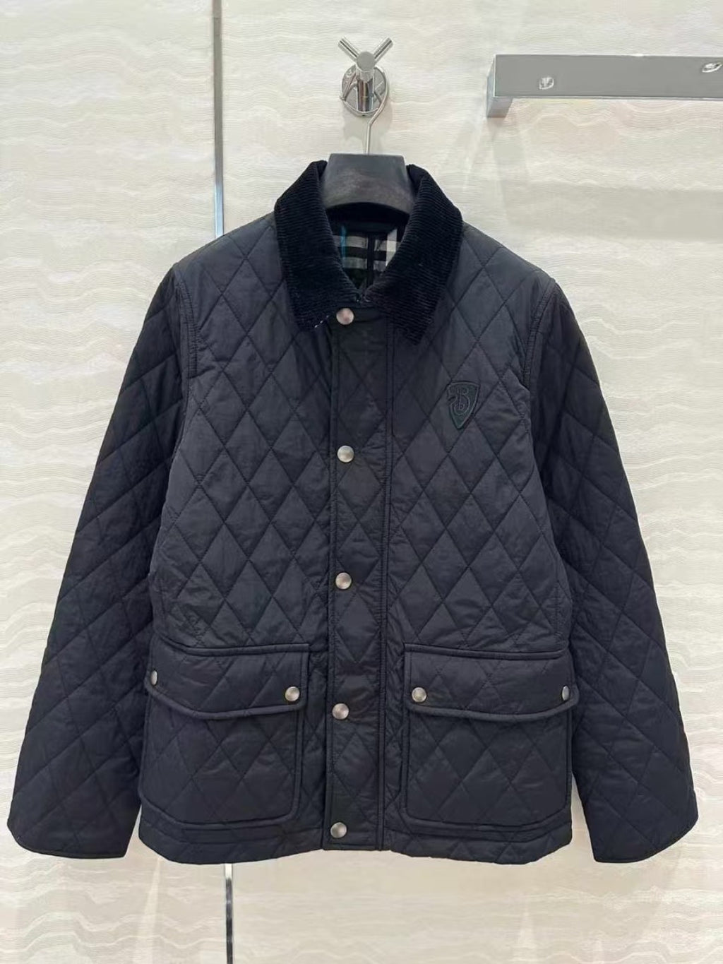 Dark quilted jacket with stand collar, snap button front, and patch pockets