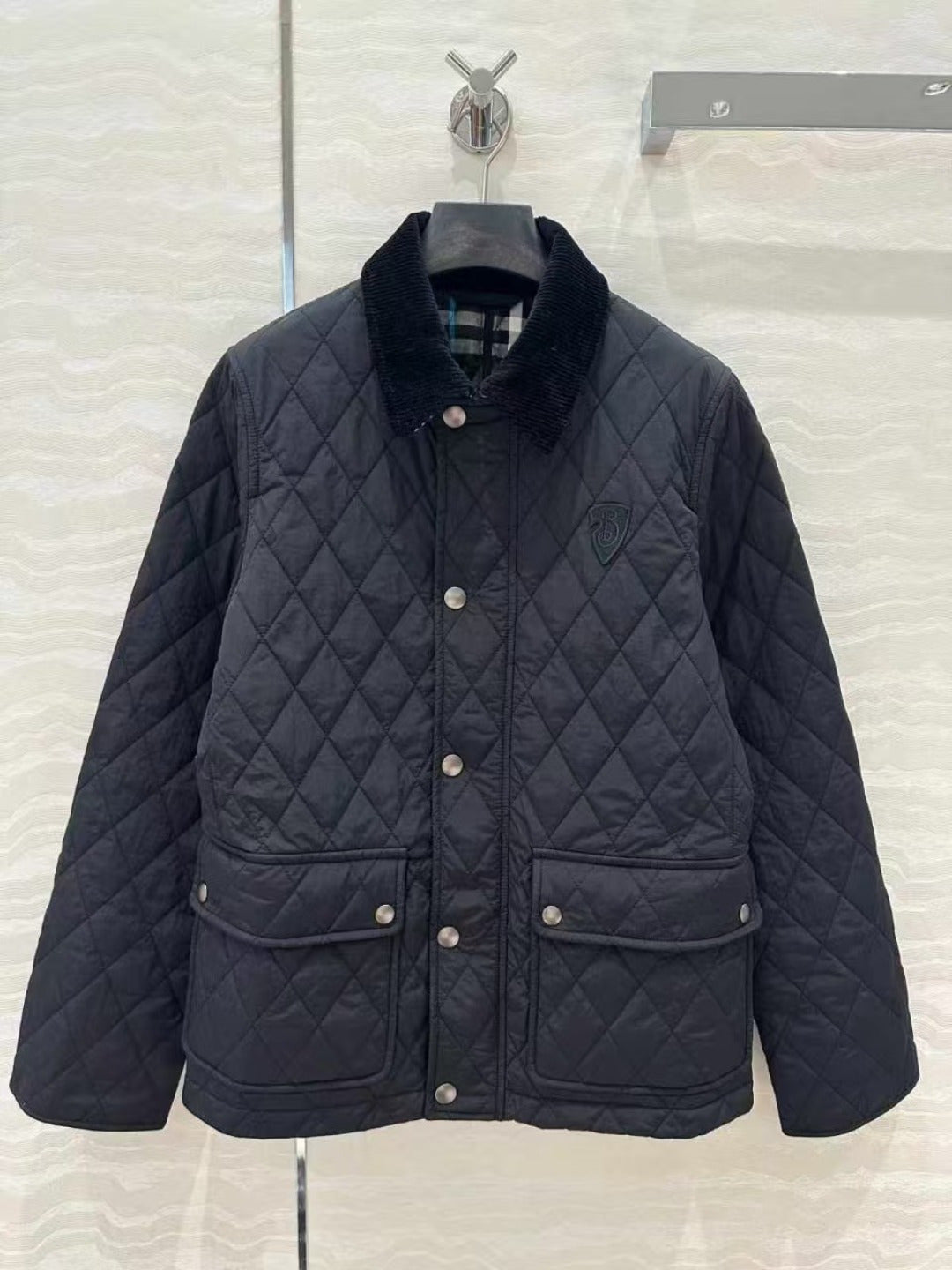 Dark quilted jacket with stand collar, snap button front, and patch pockets