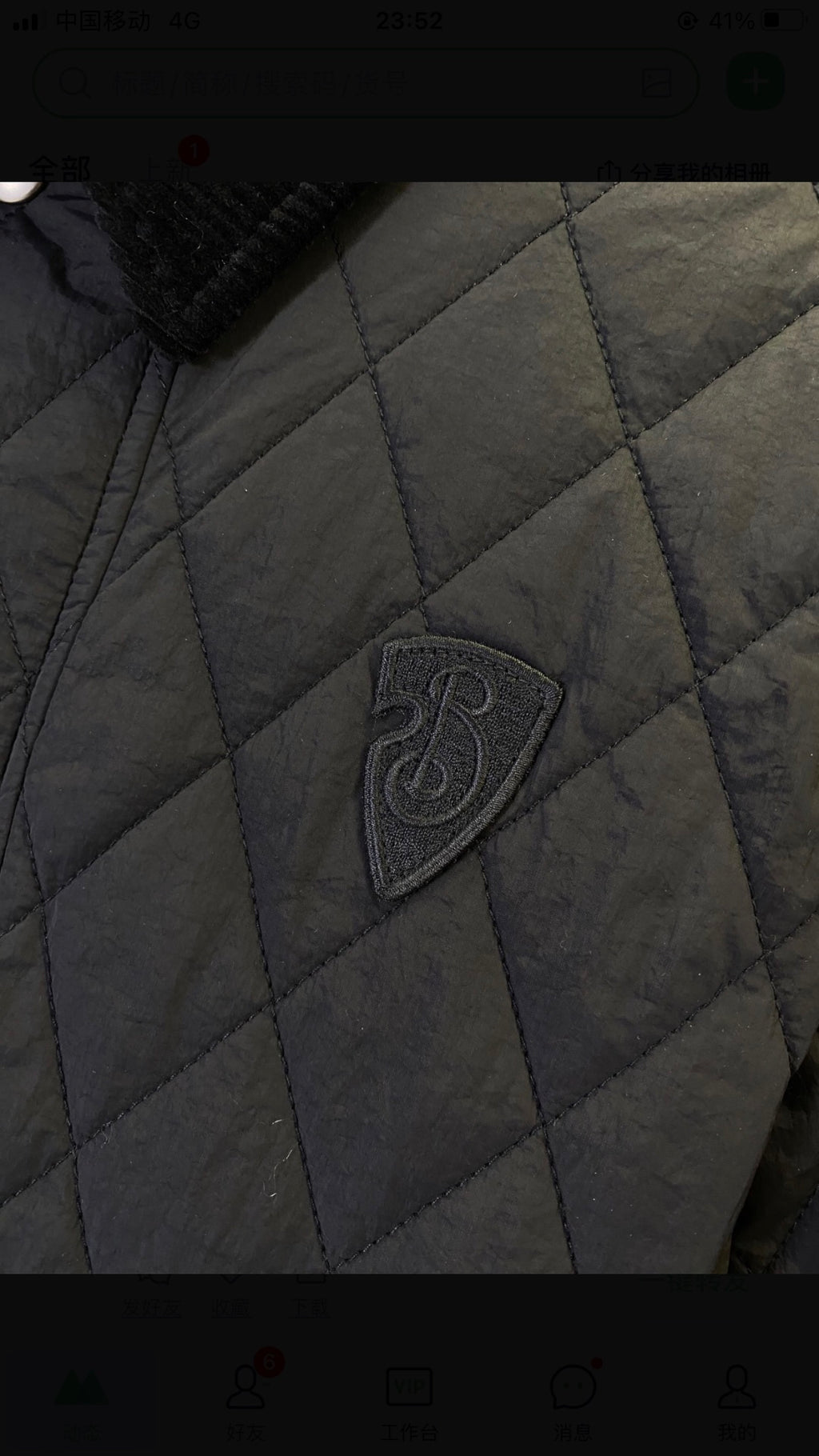 Quilted jacket fabric close-up with dark logo badge on the chest