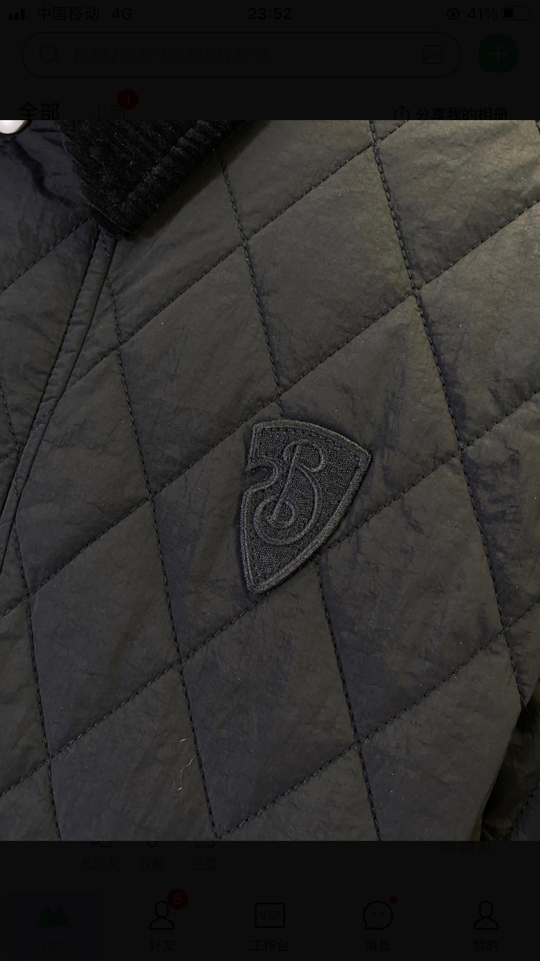 Quilted jacket fabric close-up with dark logo badge on the chest