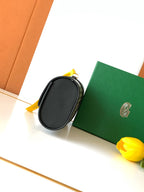 Goyard small oval crossbody bag with black leather strap and yellow key charm
