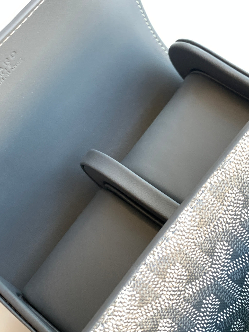 Goyard bag lining detail with gray leather panels and rounded compartment