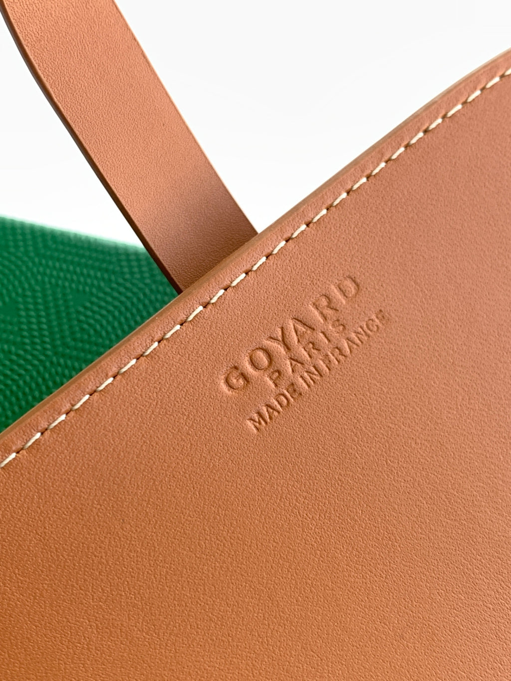 Tan leather Goyard bag detail with embossed logo and stitched edge