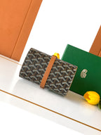 Goyard bag, front view: dark monogram canvas with tan leather buckle strap