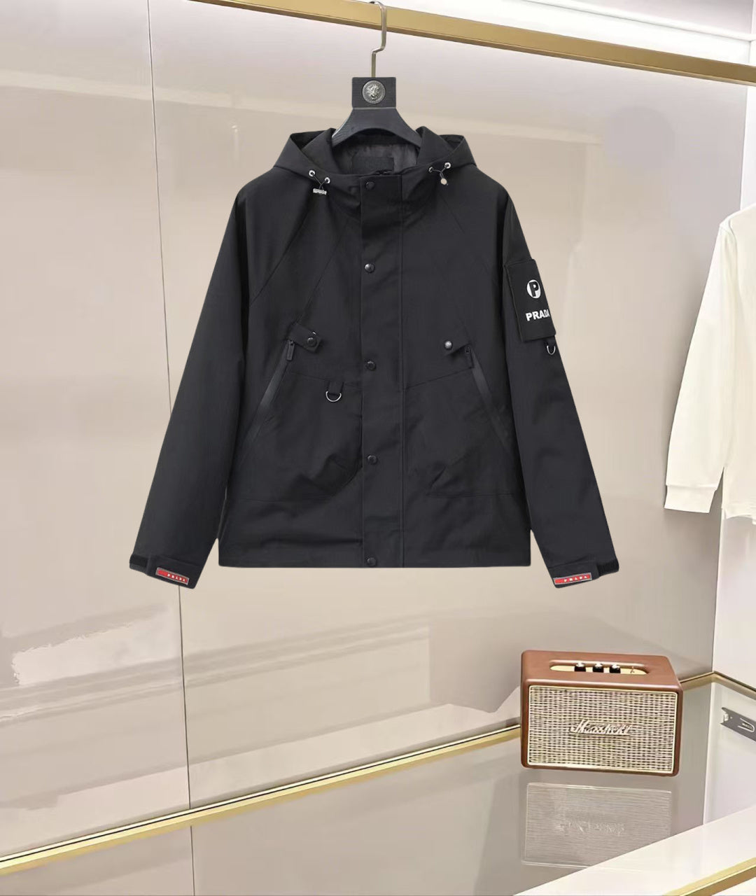 Black hooded coat with button front, flap pockets, and Prada logo patch