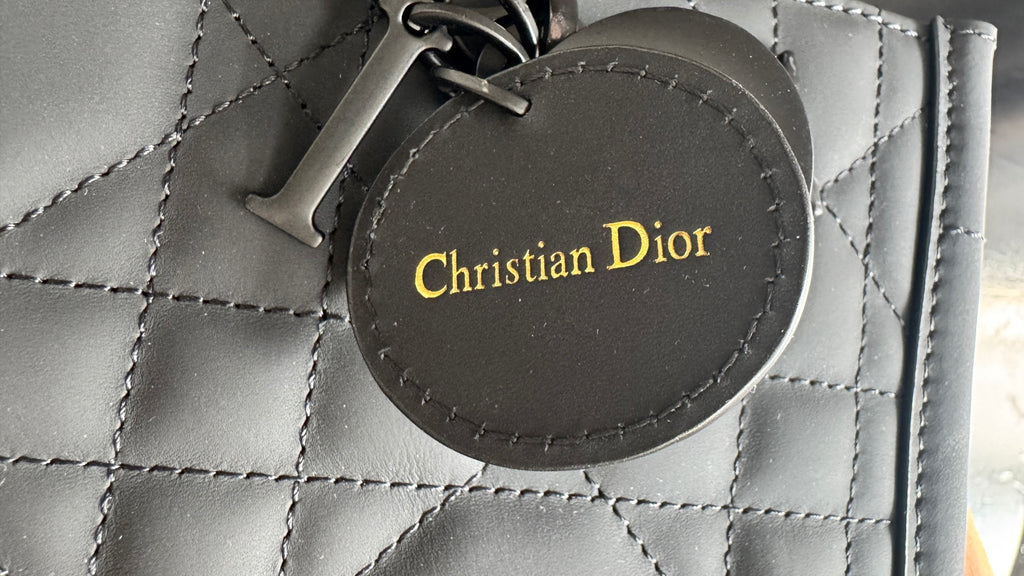 Christian Dior round logo patch on quilted bag, with stitched border on dark leather