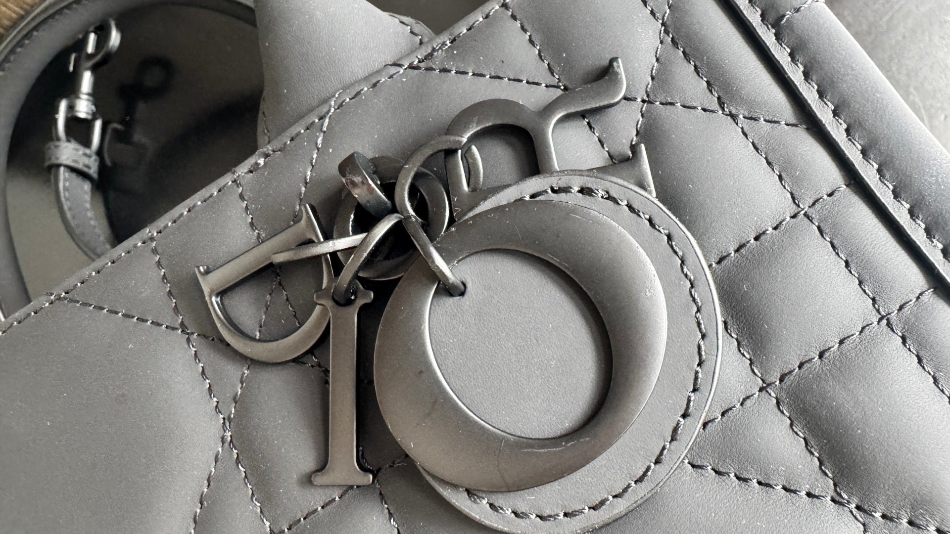 Dior hardware clasp on quilted leather bag, dark metal ring and engraved details