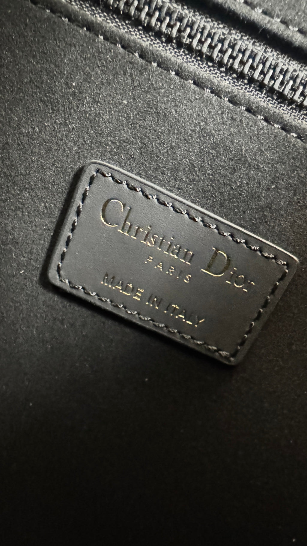 Christian Dior leather logo patch on dark gray bag with stitched border