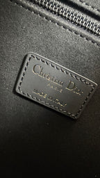 Christian Dior leather logo patch on dark gray bag with stitched border