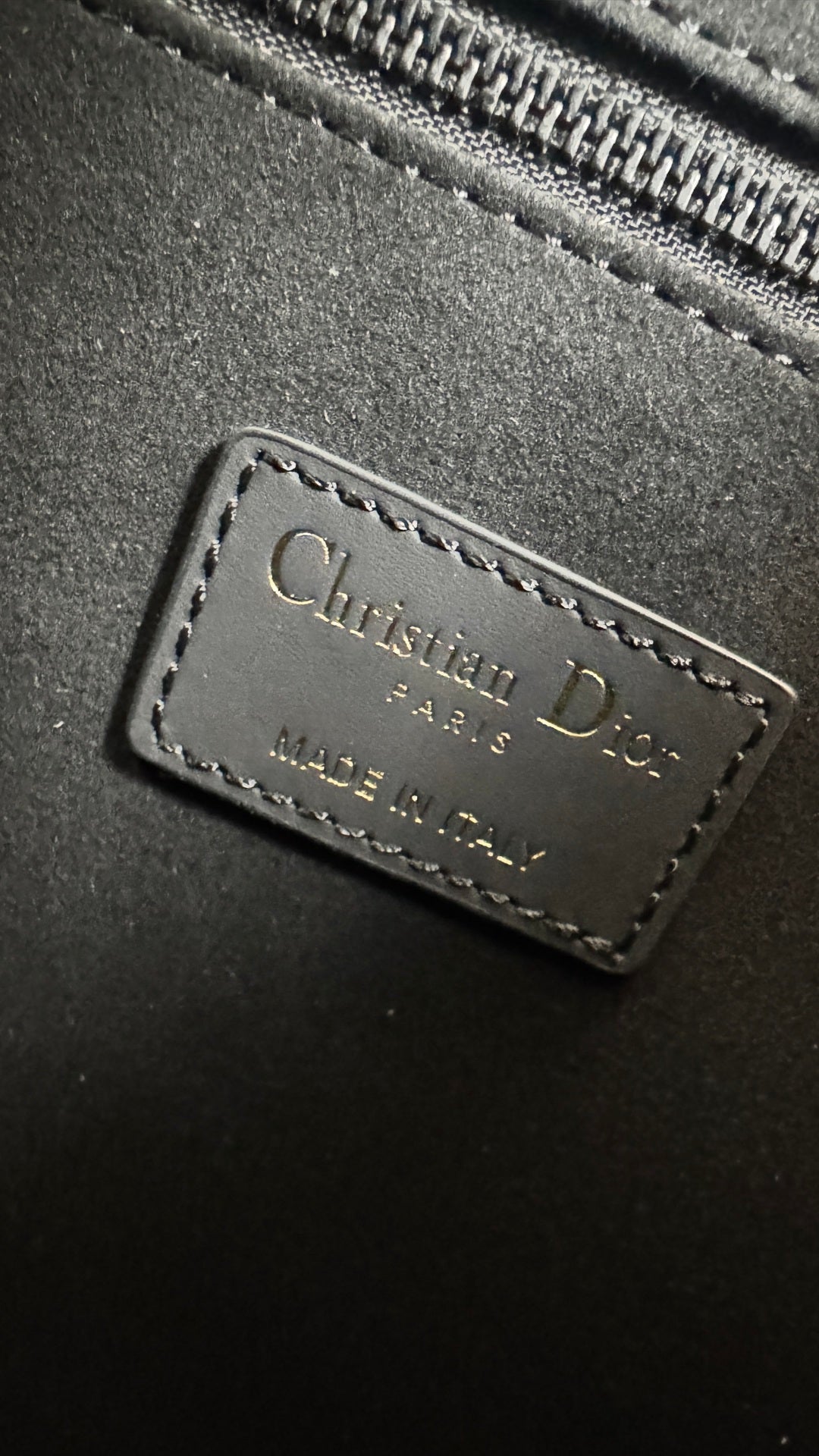 Christian Dior leather logo patch on dark gray bag with stitched border