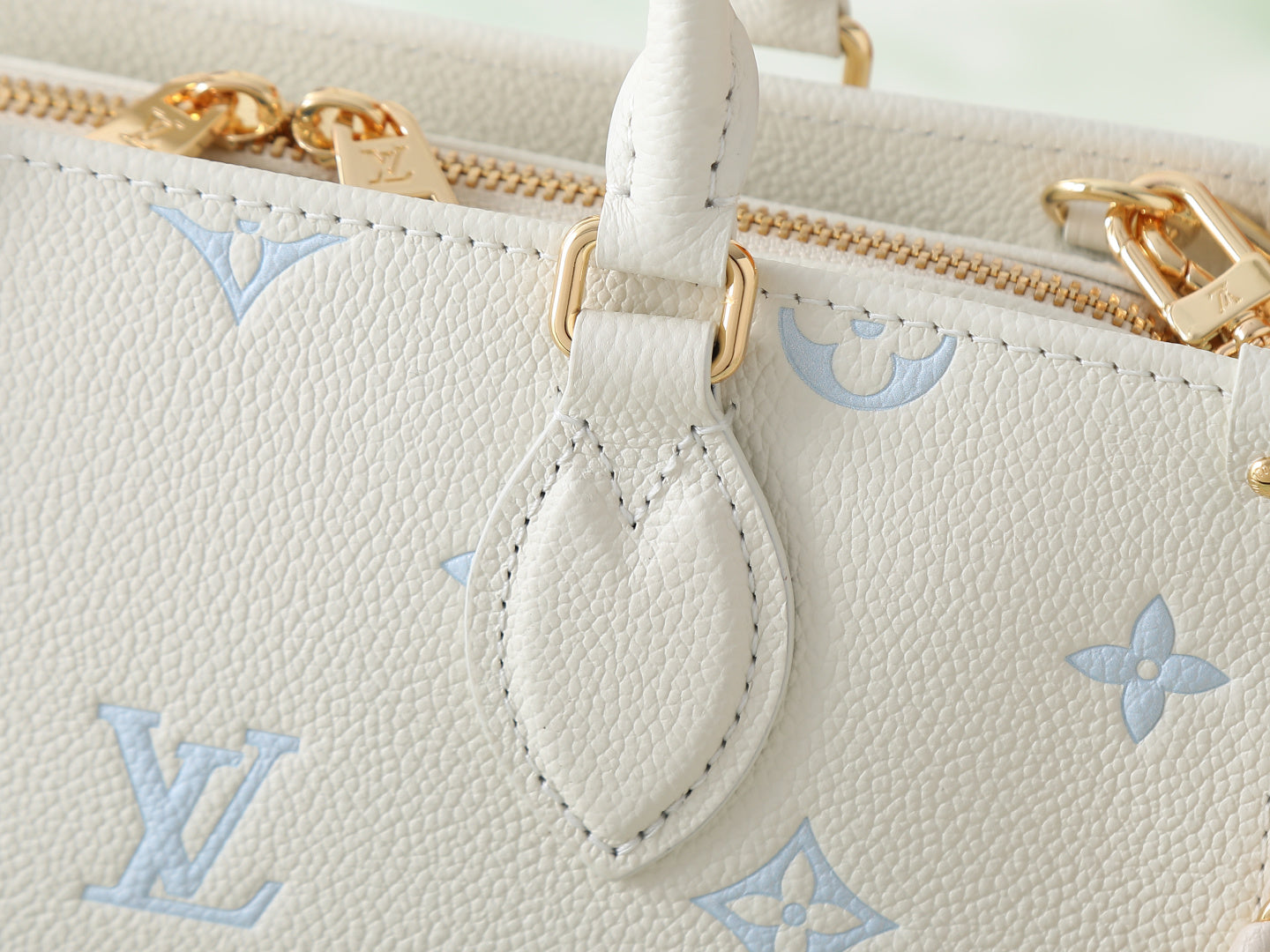 Louis Vuitton bag detail: white leather strap loop with light blue monogram pattern