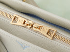 Louis Vuitton bag zipper close-up with gold pull and light blue monogram on white leather