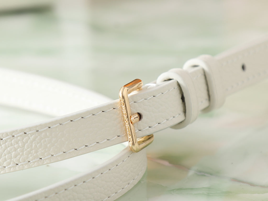 Louis Vuitton bag strap detail with gold-tone buckle on white leather