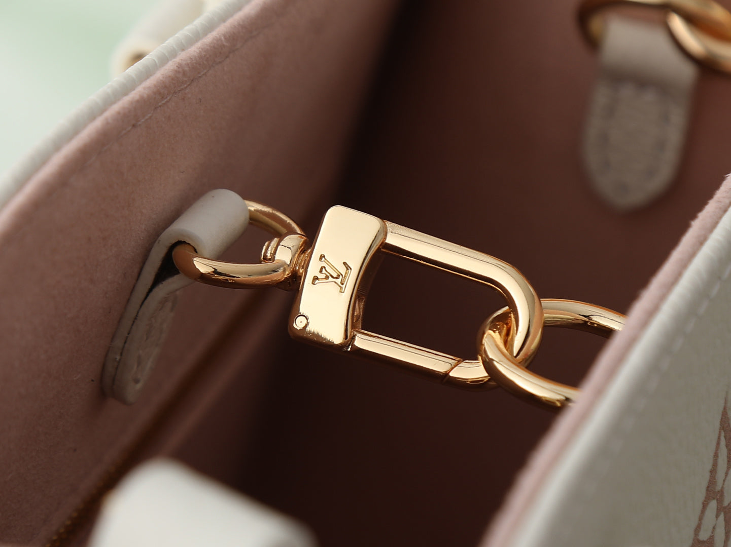 Louis Vuitton bag detail with gold-tone turn-lock clasp and pink interior lining