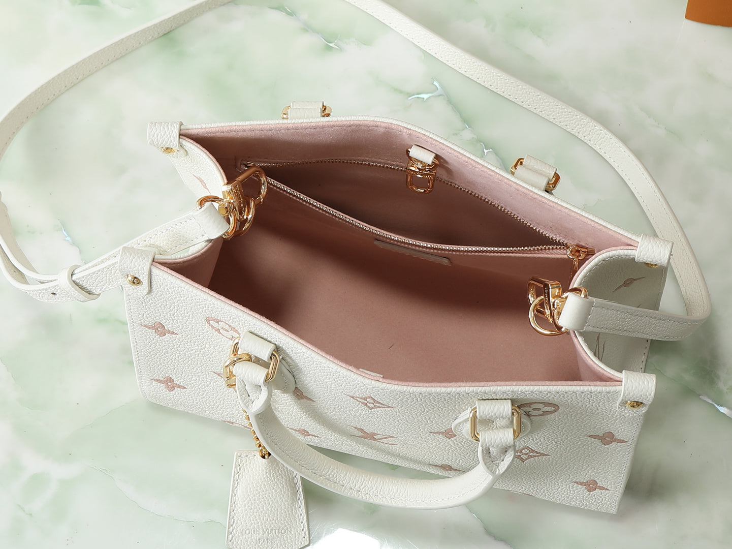 Louis Vuitton bag interior view with pink lining, zip pocket, and monogram exterior