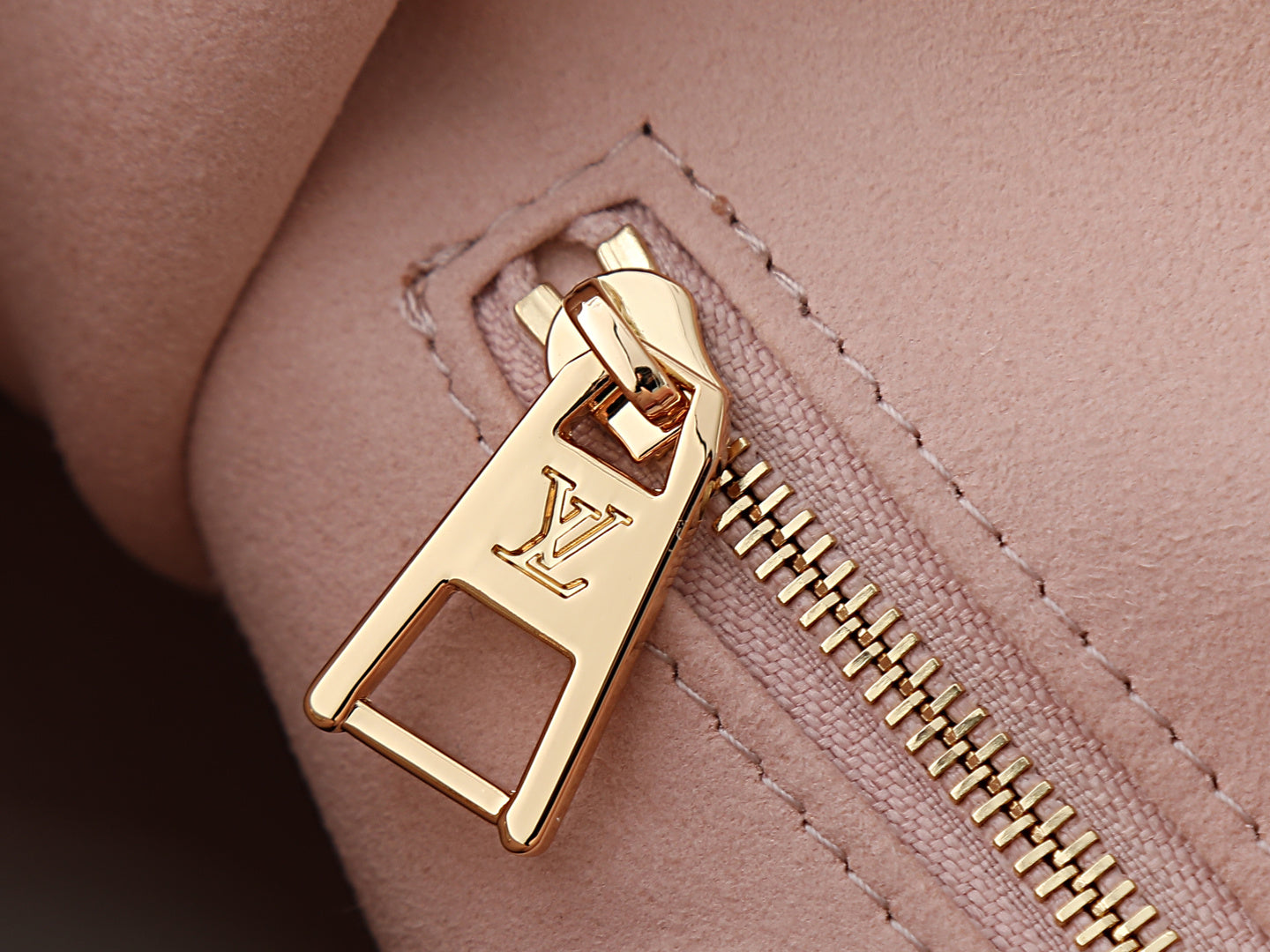 Louis Vuitton bag clasp and gold-tone zipper pull on pink leather.