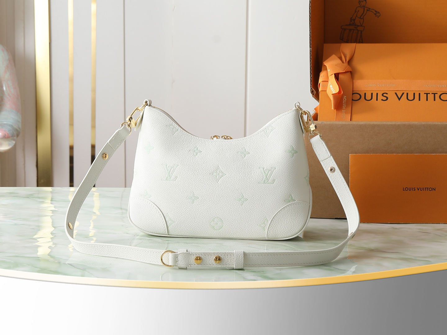 White hobo bag with white shoulder strap and gold chain detail