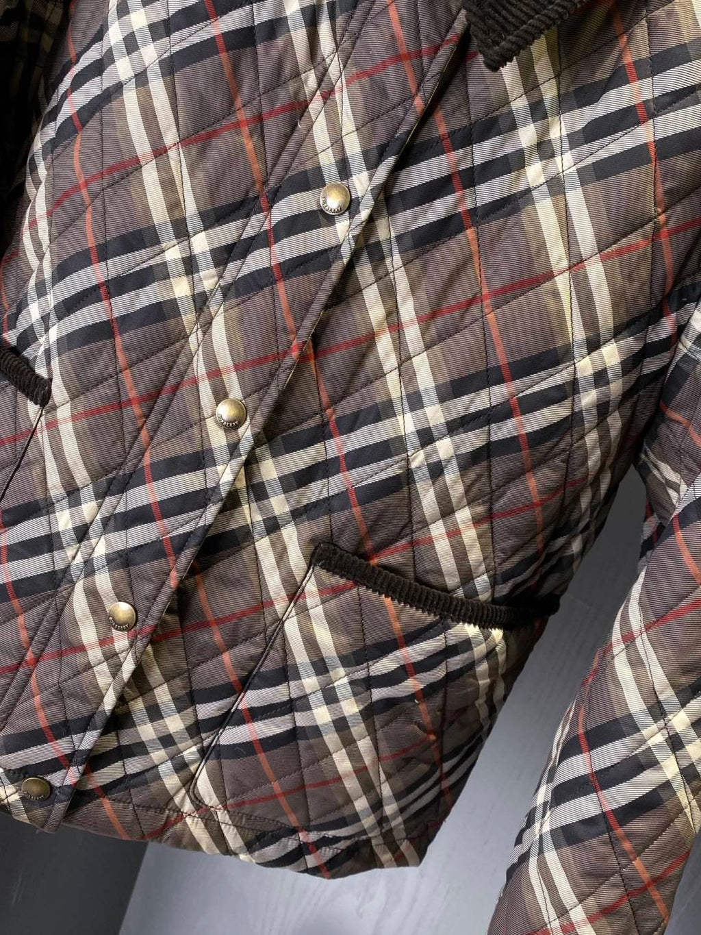 Burberry quilted plaid jacket close-up with metal buttons and drawstring hem