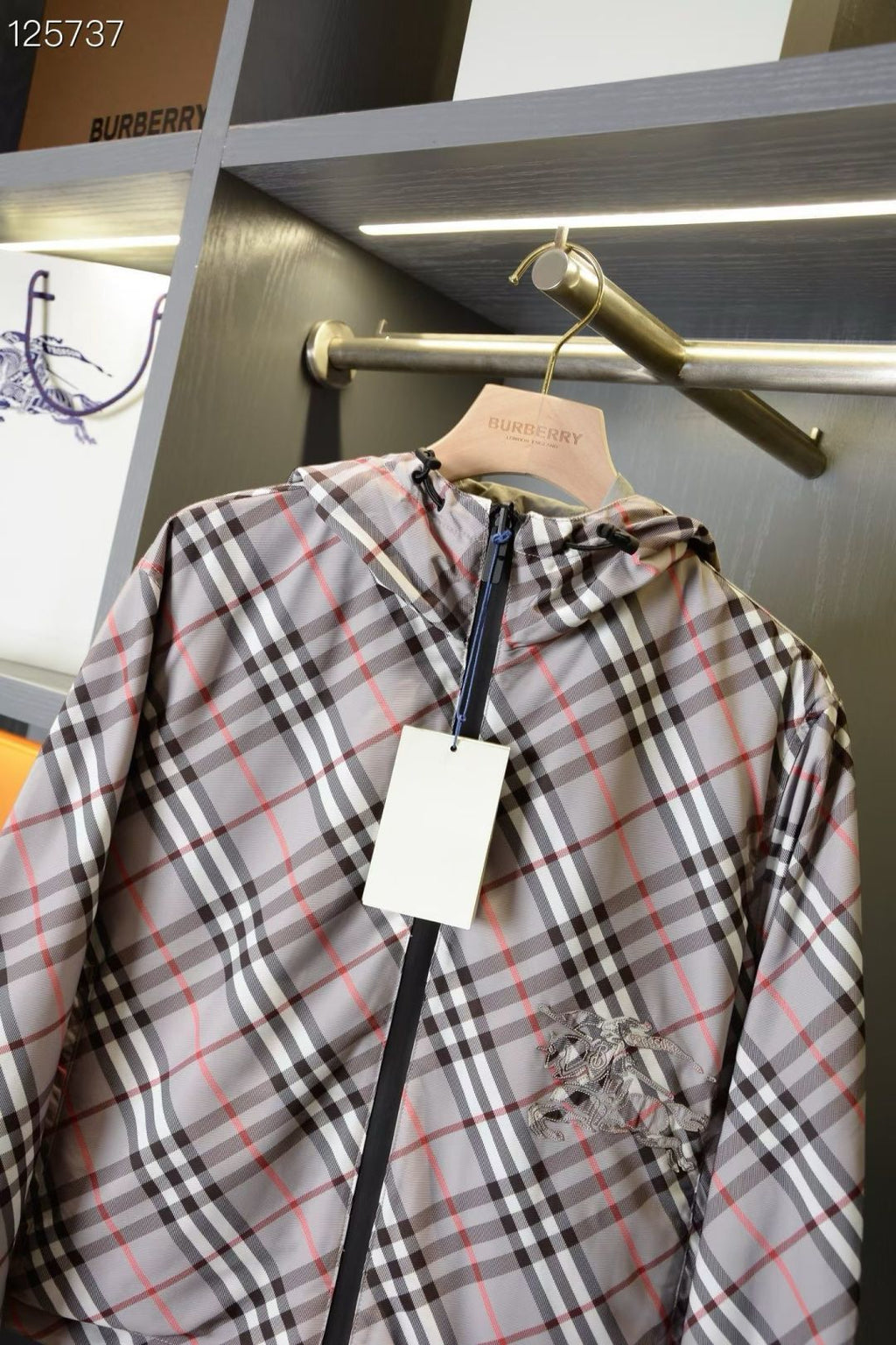 Plaid jacket with front zipper, hood, and horse logo patch on the chest