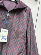 Burberry plaid hooded jacket with embroidered crest detail and zip placket.