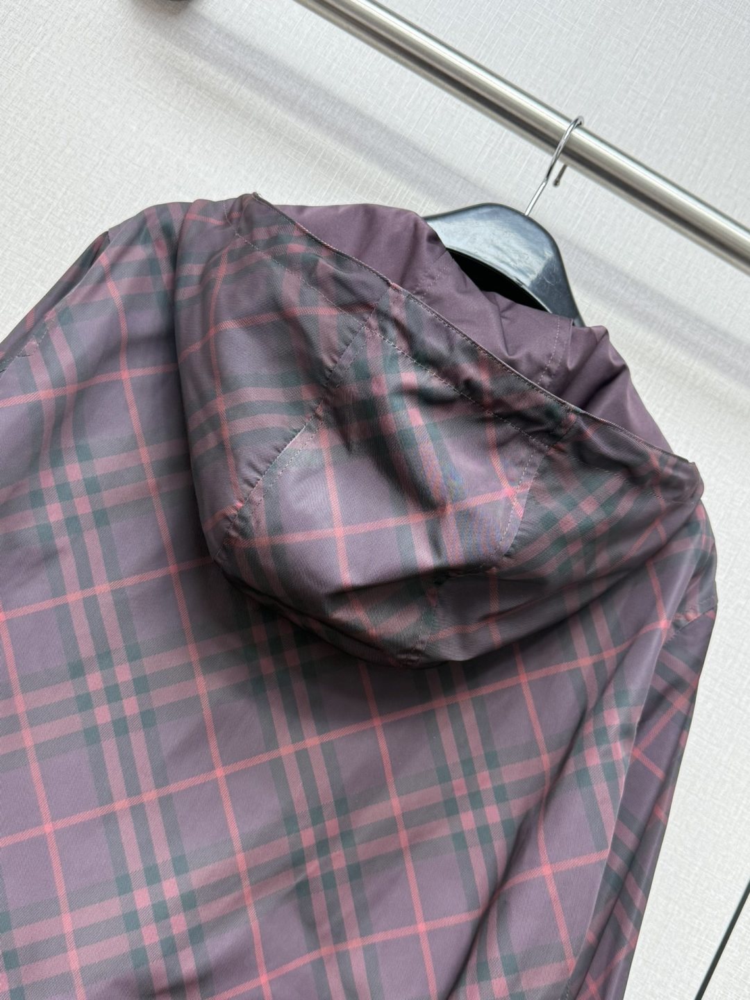 Burberry plaid hooded jacket with folded hood and zip front in dark purple.