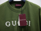 Olive green T-shirt with white Gucci logo and maroon hang tag