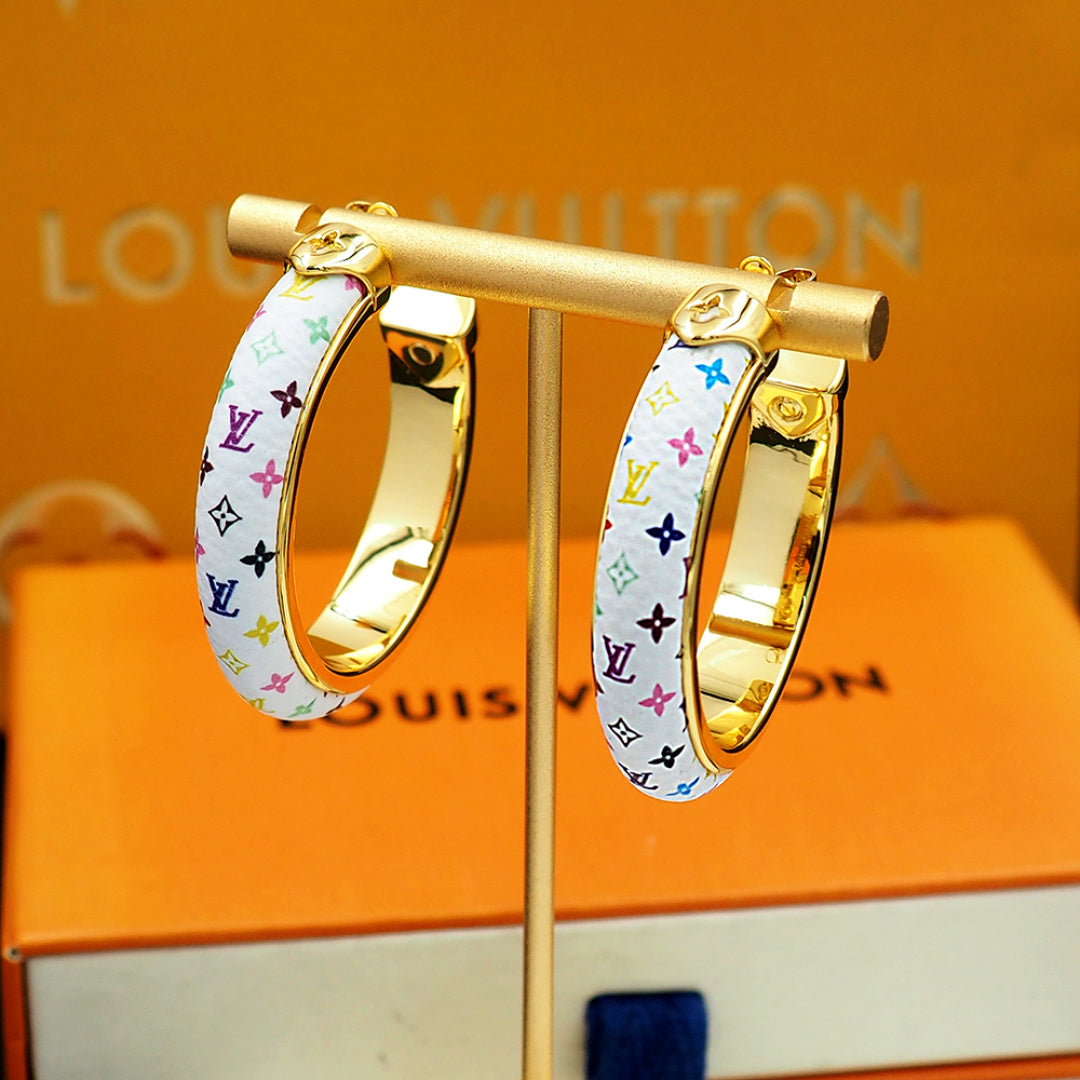 Louis Vuitton monogram hoop earrings close-up on stand, gold trim and multicolor pattern