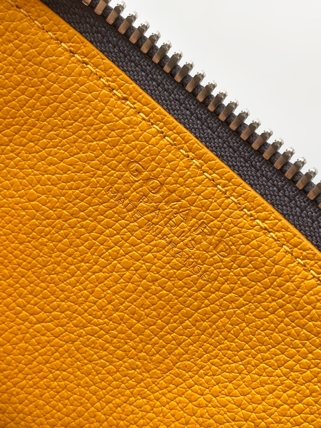 Yellow pebbled leather panel with dark stitching and zipper edge