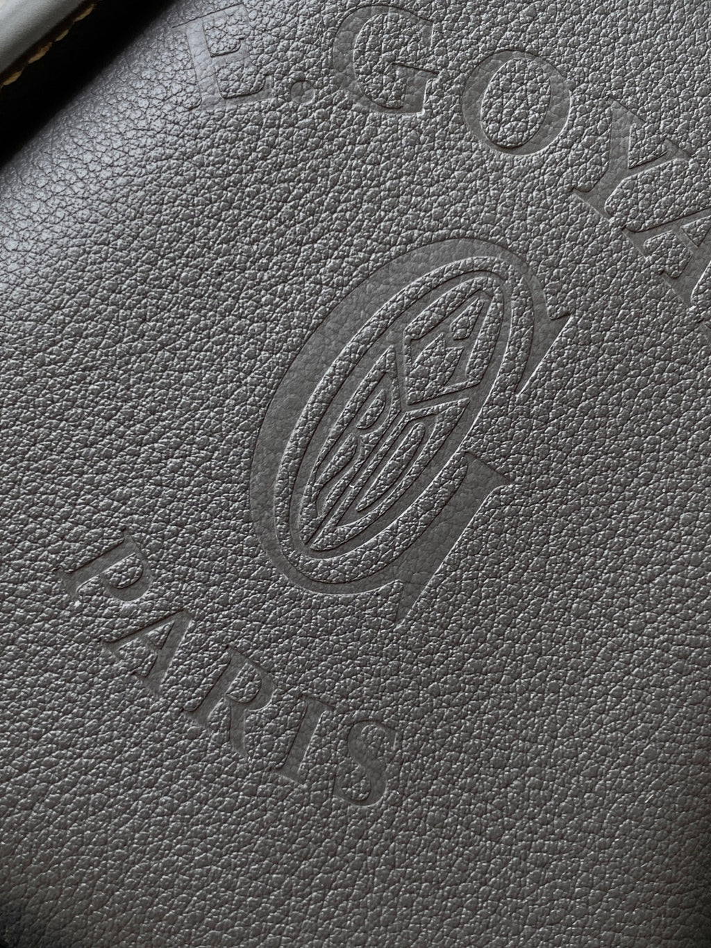 Embossed monogram leather panel in dark gray with circular emblem