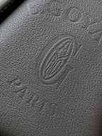 Embossed monogram leather panel in dark gray with circular emblem
