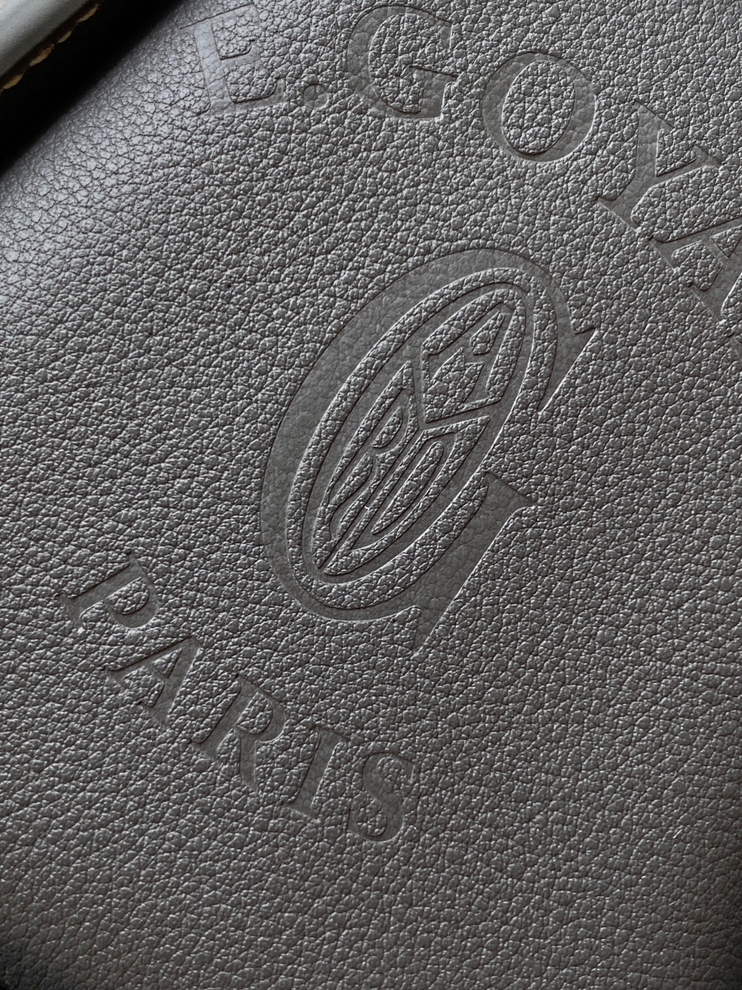 Embossed monogram leather panel in dark gray with circular emblem
