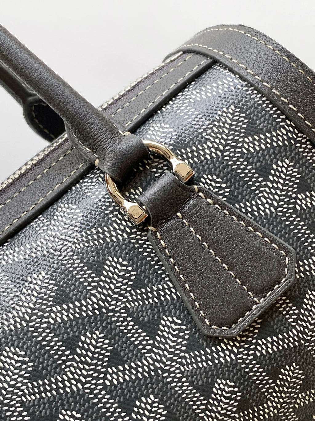 Monogram canvas handbag corner with stitched leather strap and gold buckle