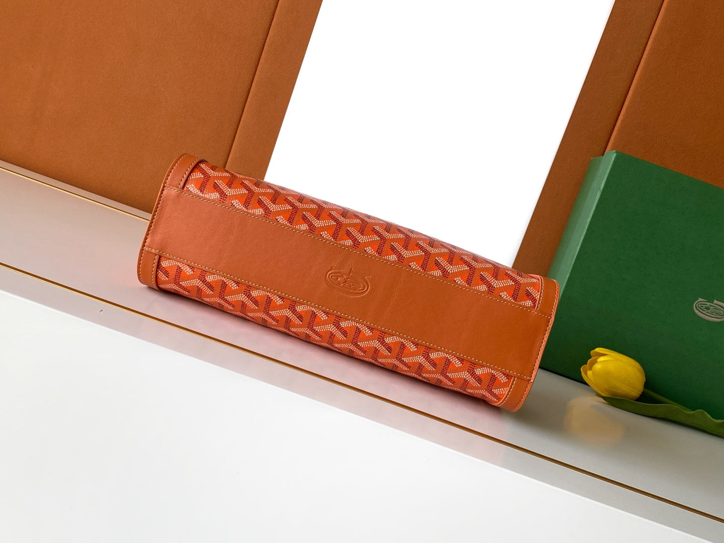 Orange patterned Goyard clutch-style bag with foldover front and short handle