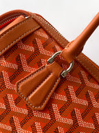 Orange patterned Goyard bag interior pocket with leather trim and metal clasp