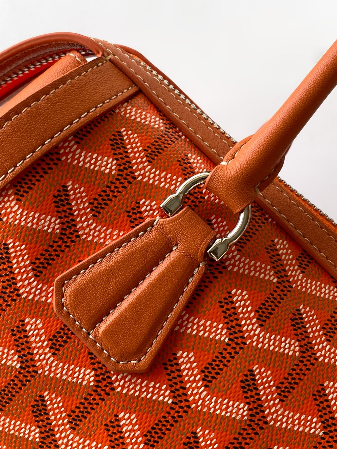 Orange patterned Goyard bag interior pocket with leather trim and metal clasp