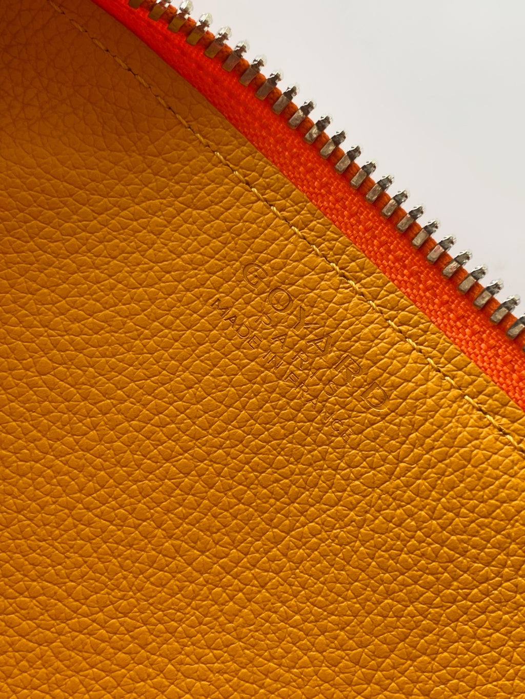 Golden leather lining with orange zipper trim on a Goyard bag