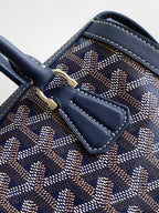 Goyard bag close-up of navy leather strap and patterned canvas with buckle tab.