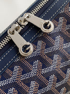 Goyard bag close-up of silver hardware and zipper pull on patterned fabric.