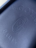 Goyard bag close-up of embossed blue leather with signature logo pattern texture.